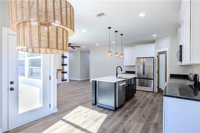 kitchen featuring pendant lighting, sink, white cabinets, stainless steel appliances, and a center island with sink