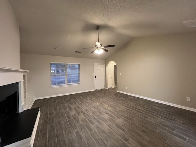 unfurnished living room with ceiling fan, lofted ceiling, dark hardwood / wood-style floors, and a textured ceiling