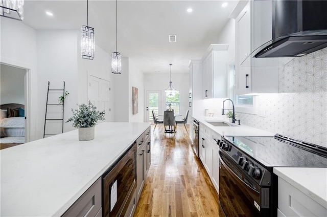 115 Dahlia Ave NW, Atlanta, GA 30314 - kitchen featuring stainless steel appliances, wall chimney range hood, light wood finished floors, tasteful backsplash, and white cabinets