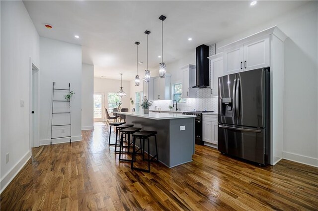 115 Dahlia Ave NW, Atlanta, GA 30314 - kitchen featuring refrigerator with ice dispenser, black range with gas stovetop, wall chimney range hood, a center island, and a breakfast bar area