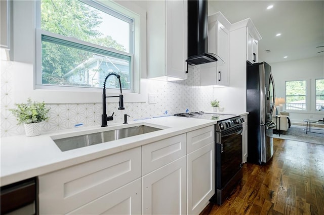 115 Dahlia Ave NW, Atlanta, GA 30314 - kitchen with black electric range, freestanding refrigerator, wall chimney exhaust hood, dark wood-style floors, and white cabinets