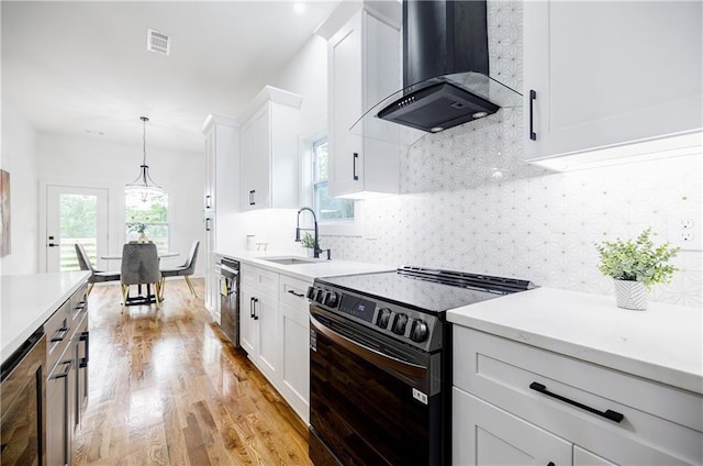 115 Dahlia Ave NW, Atlanta, GA 30314 - kitchen with electric range oven, wall chimney range hood, light wood-style flooring, and plenty of natural light