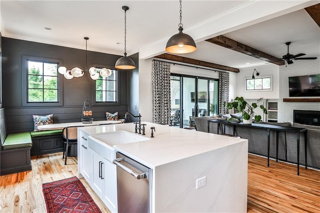 kitchen with white cabinets, a sink, a ceiling fan, light wood-type flooring, and stainless steel dishwasher