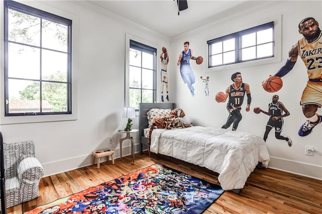 bedroom with baseboards, ornamental molding, wood finished floors, and multiple windows