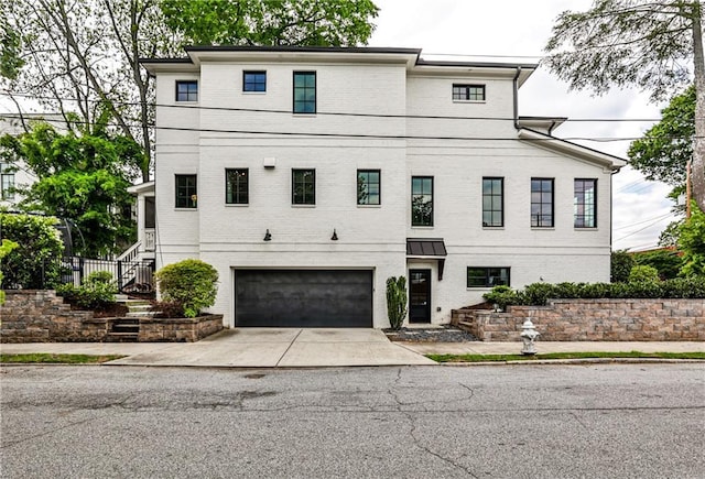 view of front of home with brick siding, stairs, an attached garage, and driveway