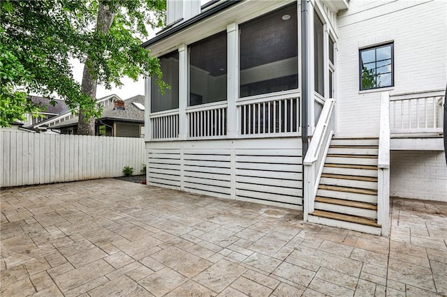 view of patio with fence, stairs, and a sunroom