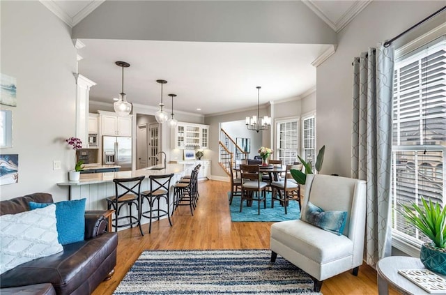 5173 Brendlynn Dr, Suwanee, GA 30024 - living area featuring light wood finished floors, a chandelier, ornamental molding, and baseboards