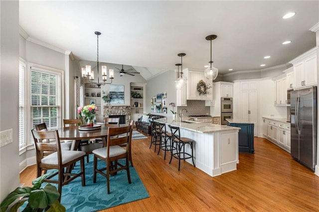 5173 Brendlynn Dr, Suwanee, GA 30024 - dining area featuring wood finished floors, crown molding, a chandelier, recessed lighting, and a stone fireplace
