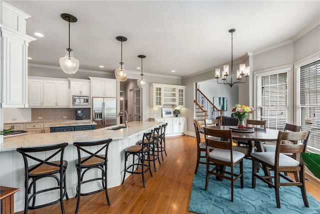 5173 Brendlynn Dr, Suwanee, GA 30024 - kitchen featuring stainless steel appliances, white cabinetry, crown molding, a chandelier, and decorative backsplash