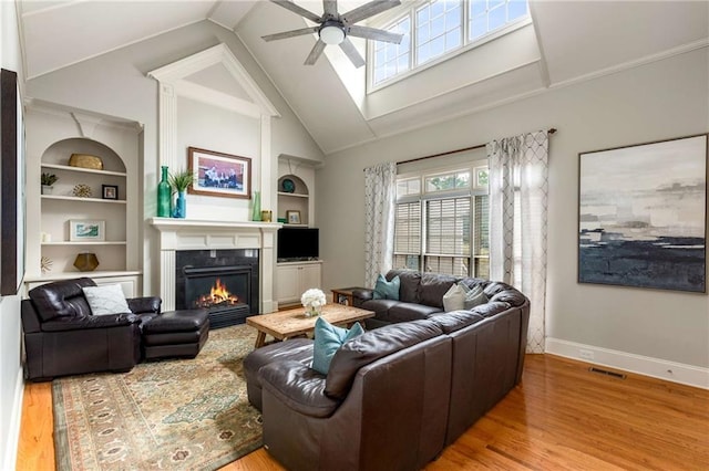 5173 Brendlynn Dr, Suwanee, GA 30024 - living area featuring ceiling fan, a glass covered fireplace, wood finished floors, built in shelves, and baseboards