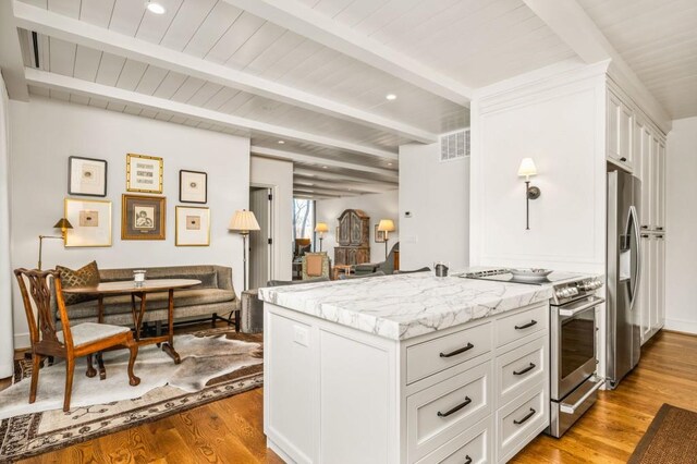 kitchen with light stone counters, visible vents, appliances with stainless steel finishes, wood finished floors, and beamed ceiling