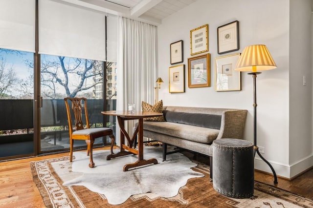 sitting room featuring beam ceiling, baseboards, and wood finished floors