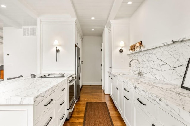 kitchen featuring visible vents, dark wood-style floors, appliances with stainless steel finishes, white cabinetry, and a sink