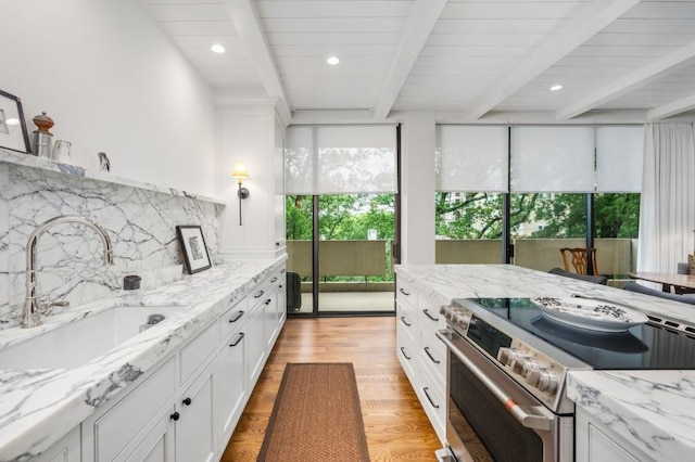 2575 Peachtree Rd NE Unit 8D, Atlanta, GA 30305 - kitchen with stainless steel electric range, a sink, beamed ceiling, backsplash, and white cabinetry