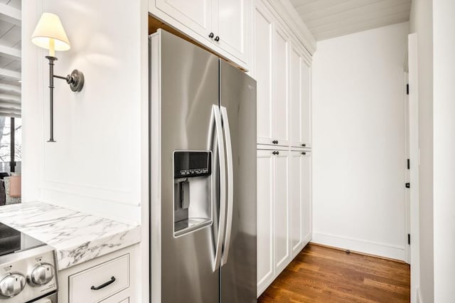 kitchen with light stone counters, dark wood-style flooring, stainless steel fridge, and white cabinets