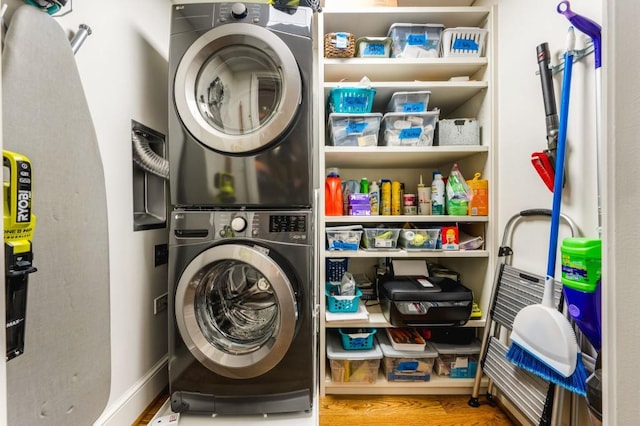 laundry area with stacked washer and dryer, wood finished floors, and laundry area