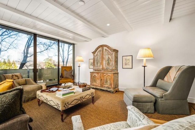 sitting room featuring baseboards, a wall of windows, and beam ceiling