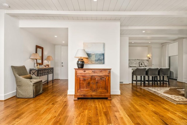 interior space with beam ceiling, baseboards, and wood finished floors