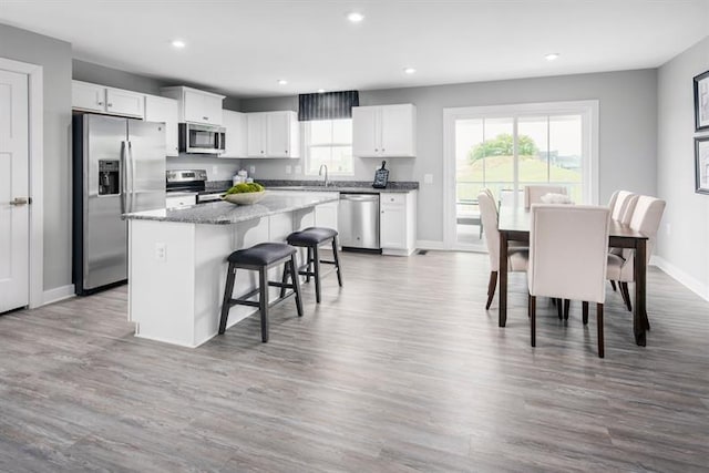 kitchen featuring a breakfast bar area, white cabinets, appliances with stainless steel finishes, and a kitchen island