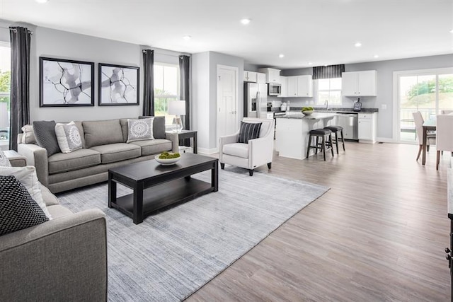 living area with recessed lighting, light wood-type flooring, and baseboards