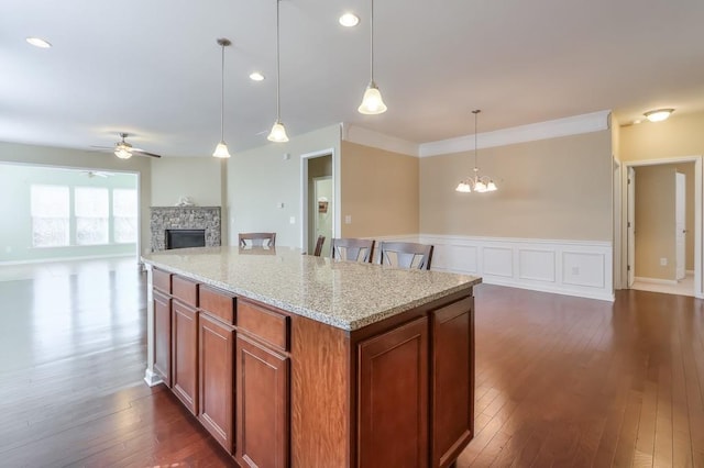 kitchen with open floor plan, dark wood-style flooring, a fireplace, and ceiling fan with notable chandelier