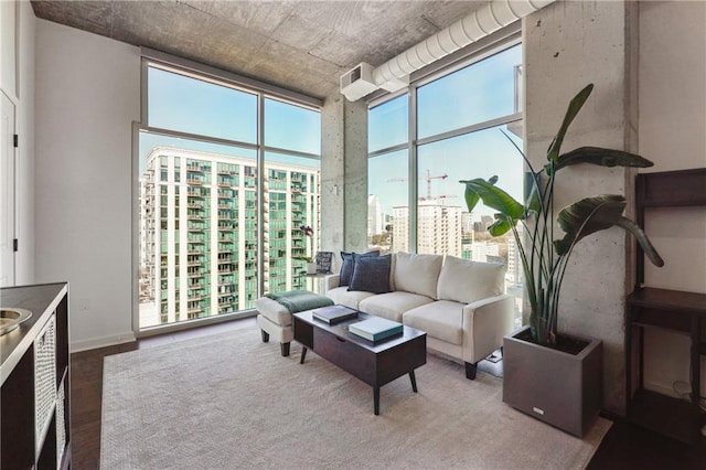 living area featuring expansive windows, a city view, a towering ceiling, and wood finished floors