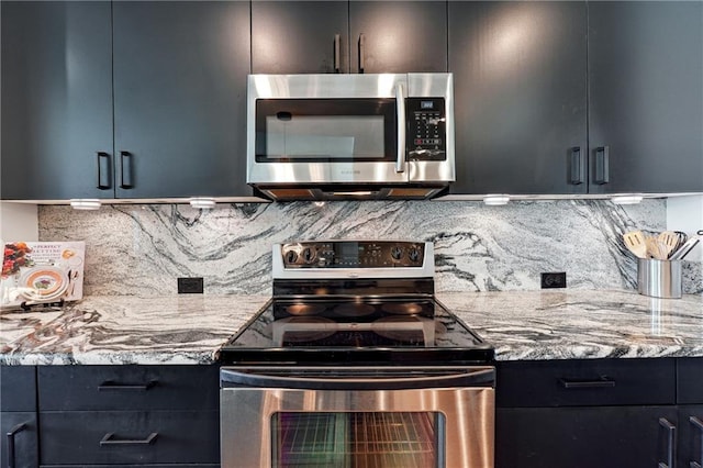 kitchen with light stone counters, backsplash, appliances with stainless steel finishes, modern cabinets, and dark cabinetry