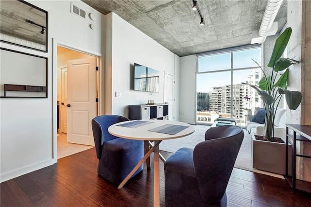 dining space featuring expansive windows, wood-type flooring, visible vents, and baseboards