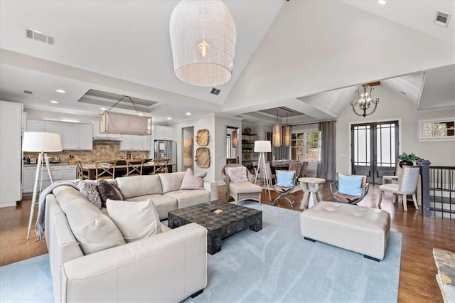 living room featuring a chandelier, light hardwood / wood-style flooring, vaulted ceiling, and a tray ceiling