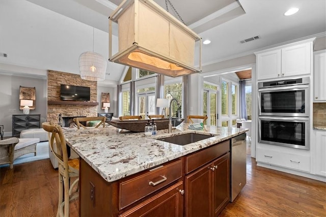 kitchen with appliances with stainless steel finishes, a kitchen bar, a fireplace, sink, and crown molding