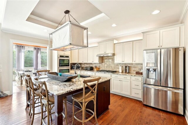 kitchen with a center island with sink, white cabinets, and light stone counters