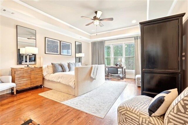 bedroom with ceiling fan, dark hardwood / wood-style floors, a tray ceiling, and ornamental molding