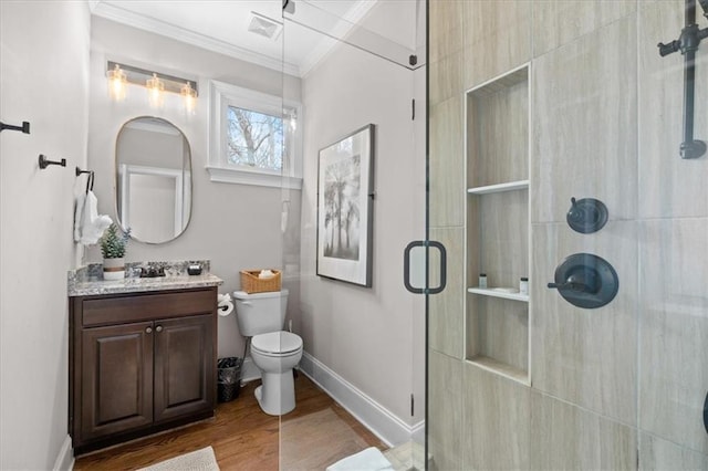 bathroom featuring wood-type flooring, vanity, toilet, ornamental molding, and a shower with shower door