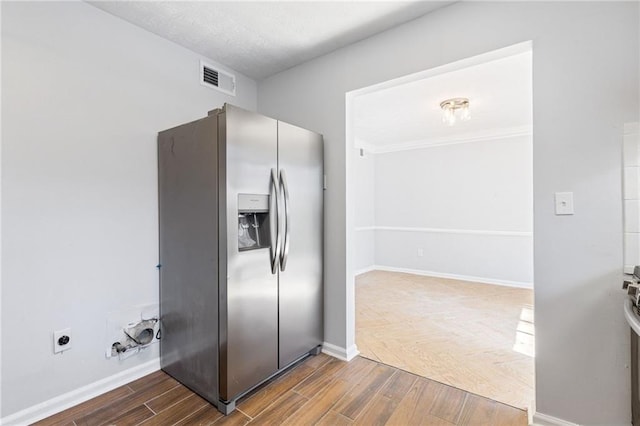 kitchen with visible vents, baseboards, stainless steel fridge, and wood finish floors