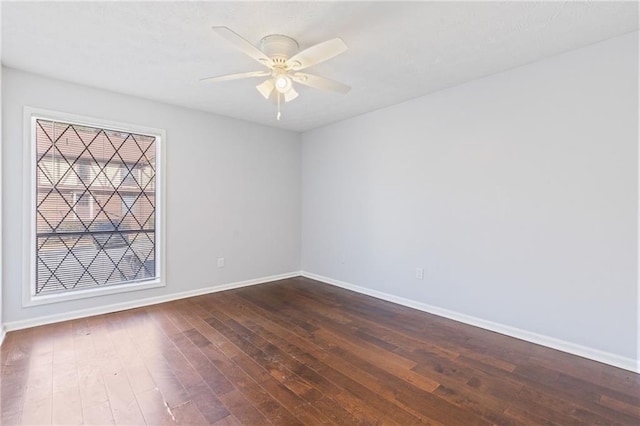 empty room featuring ceiling fan, baseboards, and dark wood-style floors