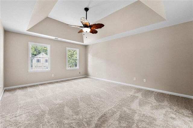 carpeted spare room featuring a raised ceiling and ceiling fan