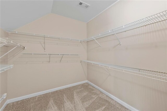 walk in closet with carpet and lofted ceiling