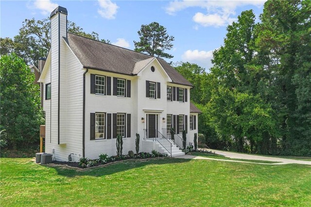 colonial-style house featuring a front yard and central air condition unit