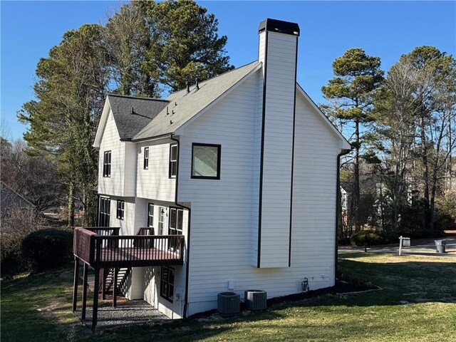 rear view of house with central air condition unit, a lawn, and a wooden deck