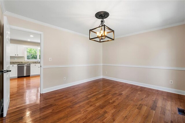 unfurnished room with a notable chandelier, wood-type flooring, and ornamental molding