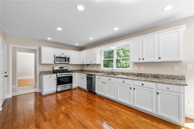 kitchen featuring white cabinets, light wood-type flooring, stainless steel appliances, and sink