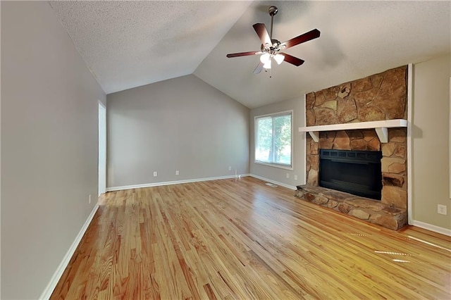 unfurnished living room featuring light hardwood / wood-style flooring, ceiling fan, a fireplace, a textured ceiling, and vaulted ceiling