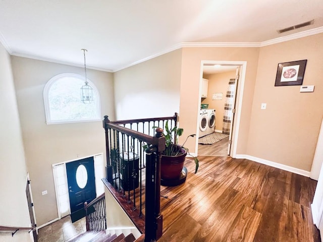 entrance foyer featuring wood-type flooring, ornamental molding, a chandelier, and washer and dryer