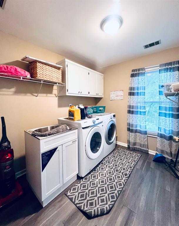 laundry area featuring dark wood-type flooring, cabinets, and washing machine and dryer