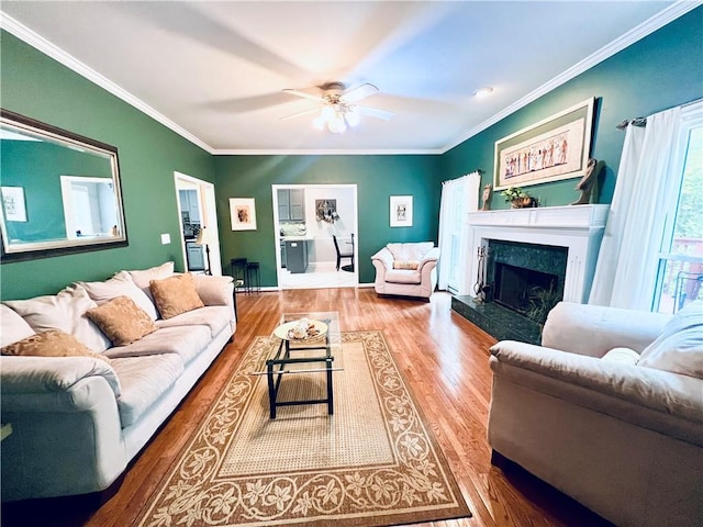 living room featuring a fireplace, ornamental molding, hardwood / wood-style floors, and ceiling fan