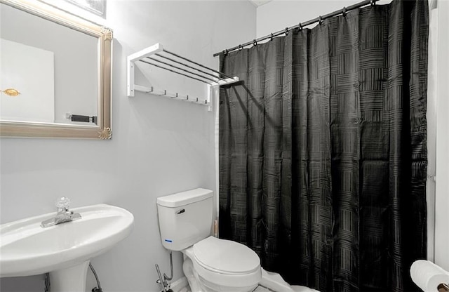 bathroom with a shower with shower curtain, toilet, and sink