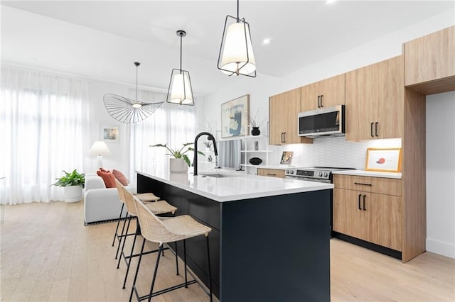 567 Ponce De Leon Ave NE Unit 614, Atlanta, GA 30308 - kitchen with appliances with stainless steel finishes, light countertops, light wood-type flooring, a breakfast bar area, and decorative backsplash