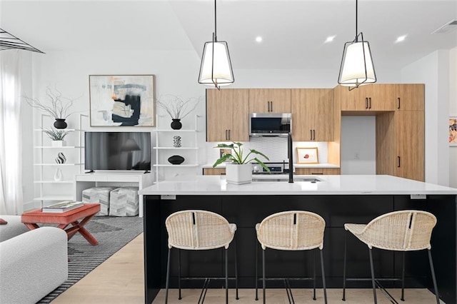 567 Ponce De Leon Ave NE Unit 614, Atlanta, GA 30308 - kitchen with stainless steel microwave, light countertops, light wood-style floors, a breakfast bar area, and an island with sink