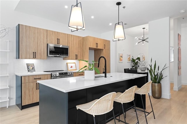 567 Ponce De Leon Ave NE Unit 614, Atlanta, GA 30308 - kitchen featuring appliances with stainless steel finishes, light countertops, light wood finished floors, a kitchen island with sink, and tasteful backsplash
