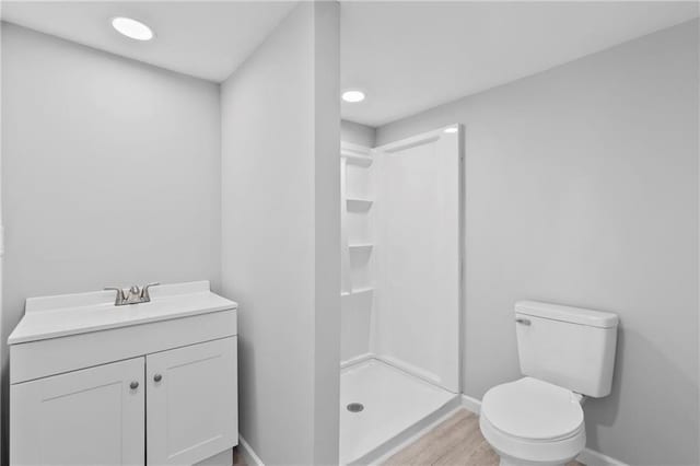 bathroom with vanity, toilet, hardwood / wood-style floors, and a shower